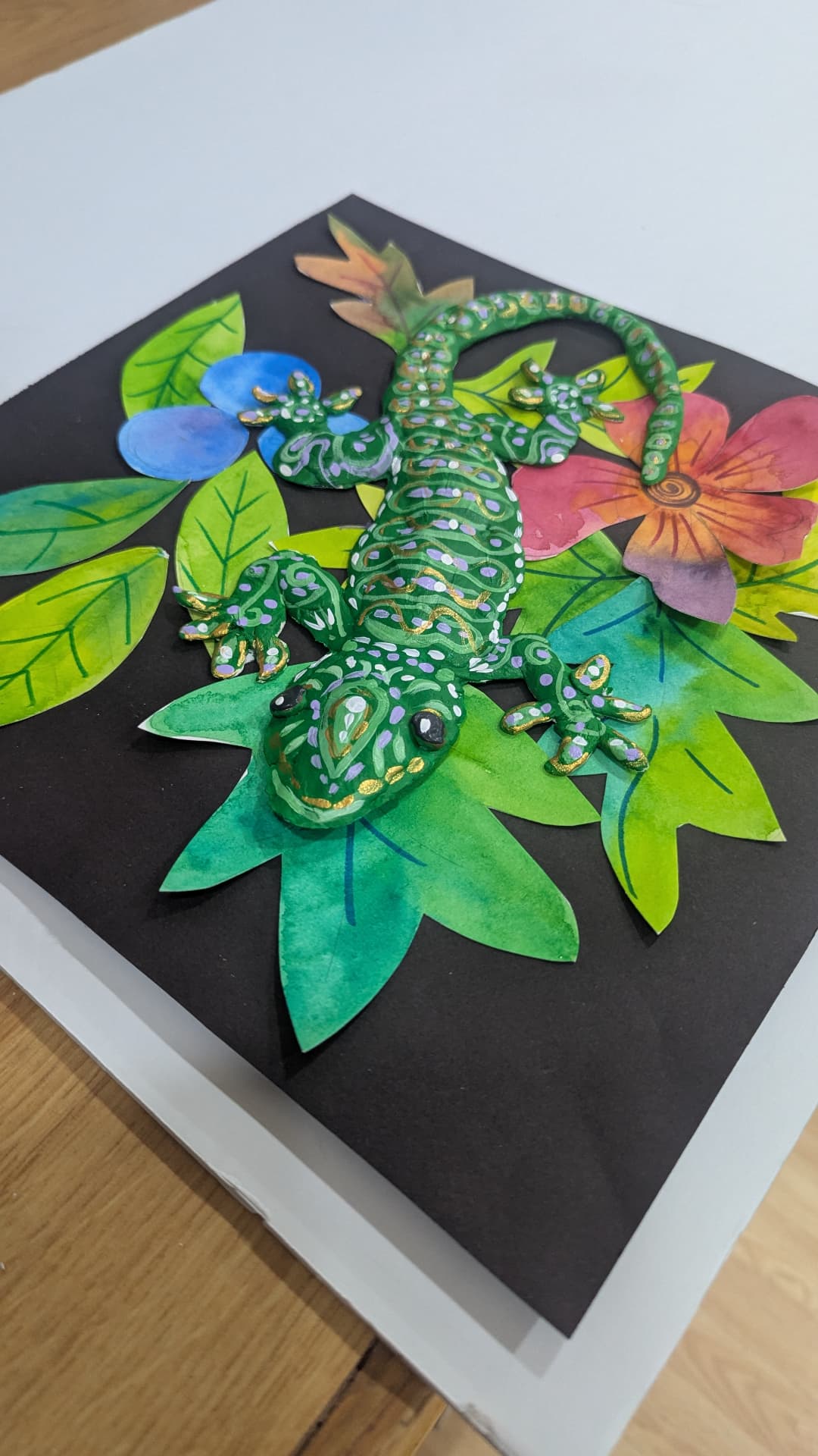 Mixed-media 3D gecko on painted leaves by a student