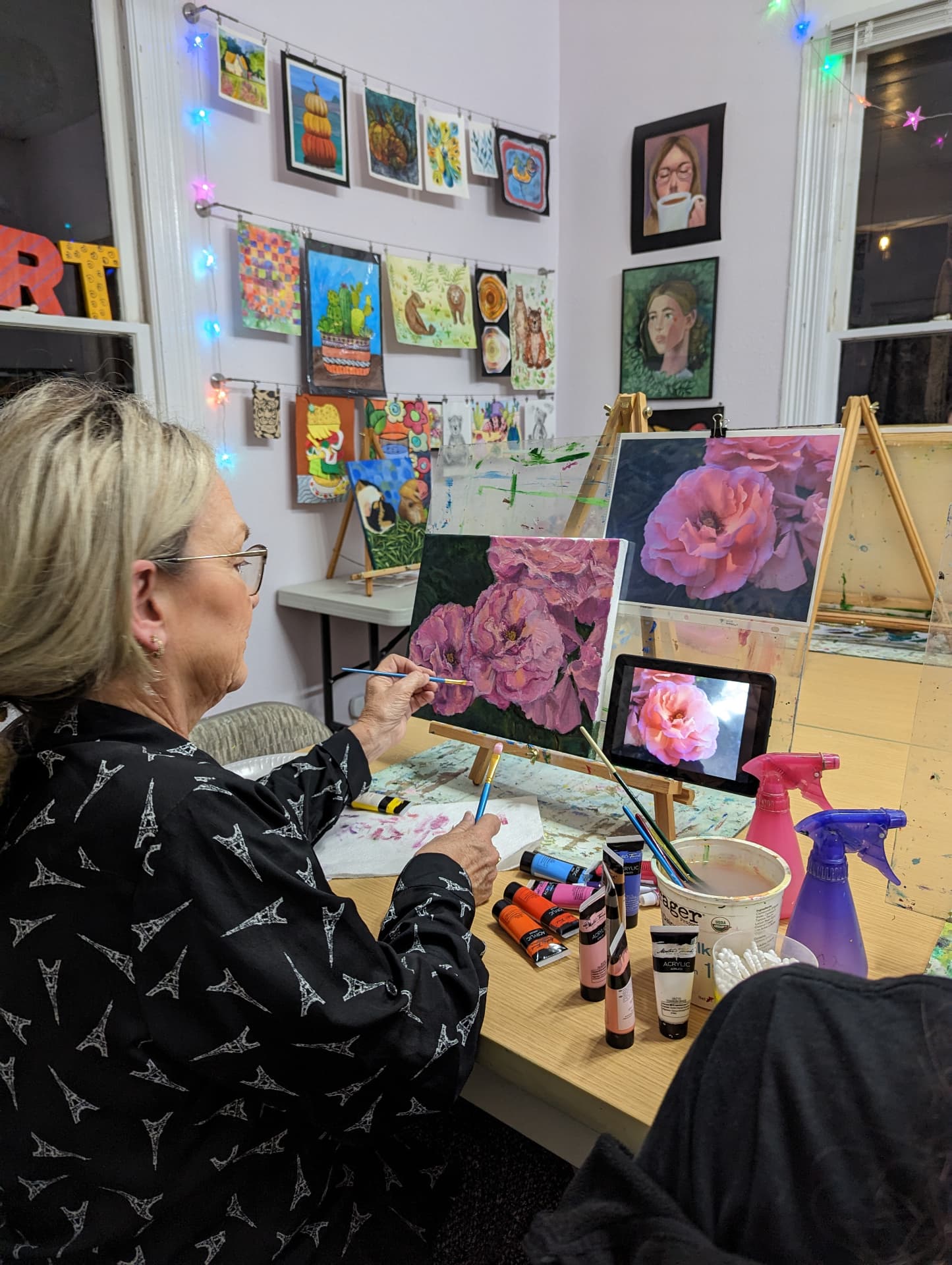 Adult student painting pink roses in oil at the studio