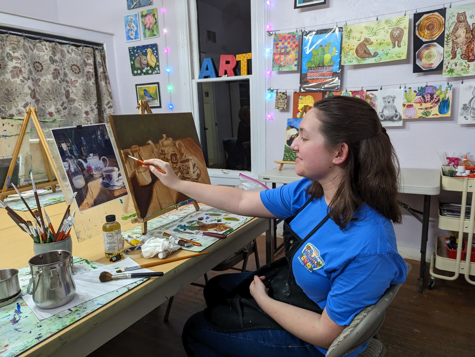 Adult student working on an oil painting of a teapot still life