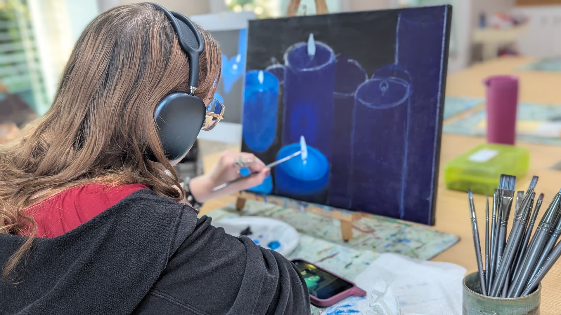Teen painting a moody still life of blue candles