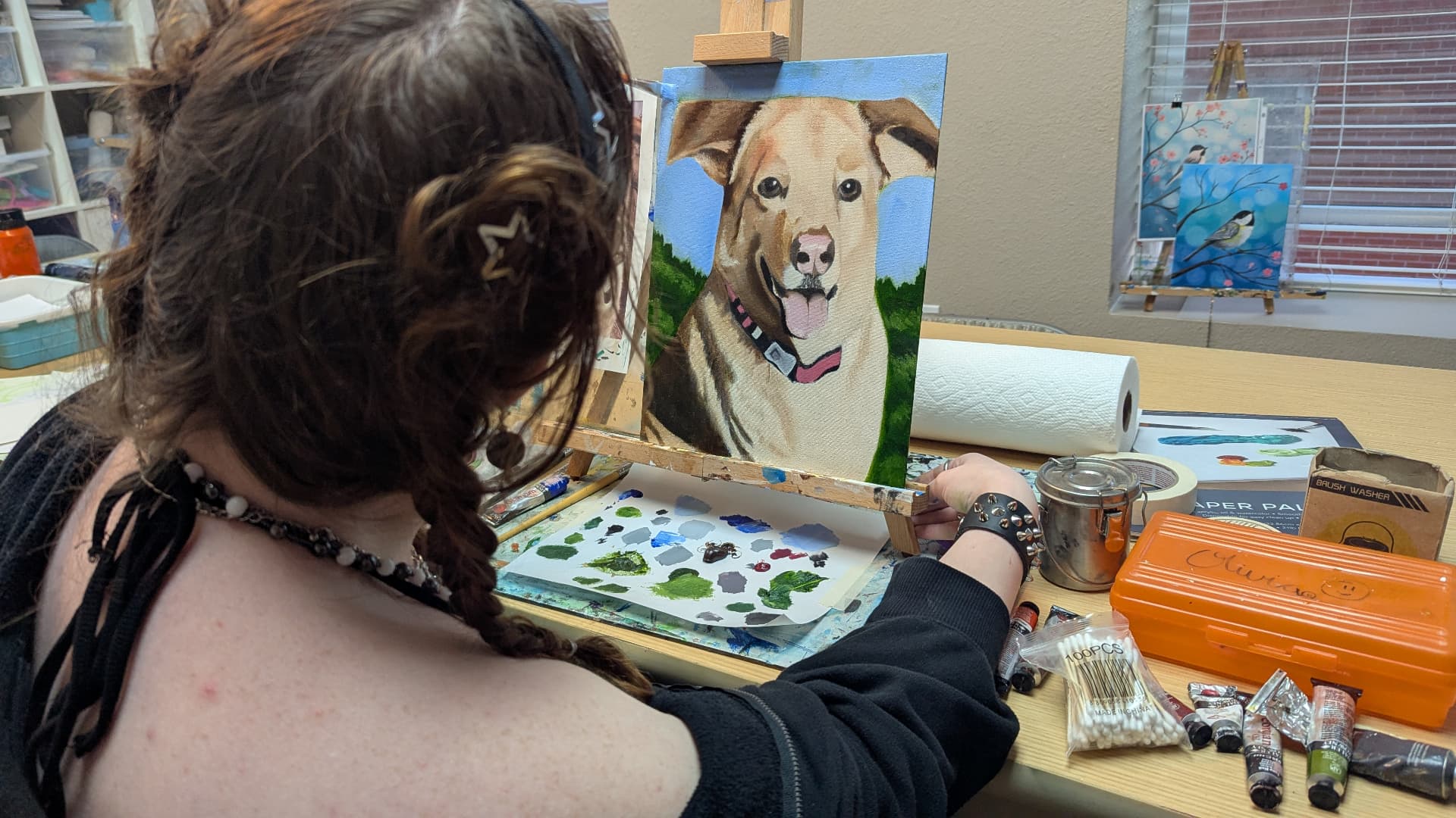 Teen painting a portrait of a golden dog