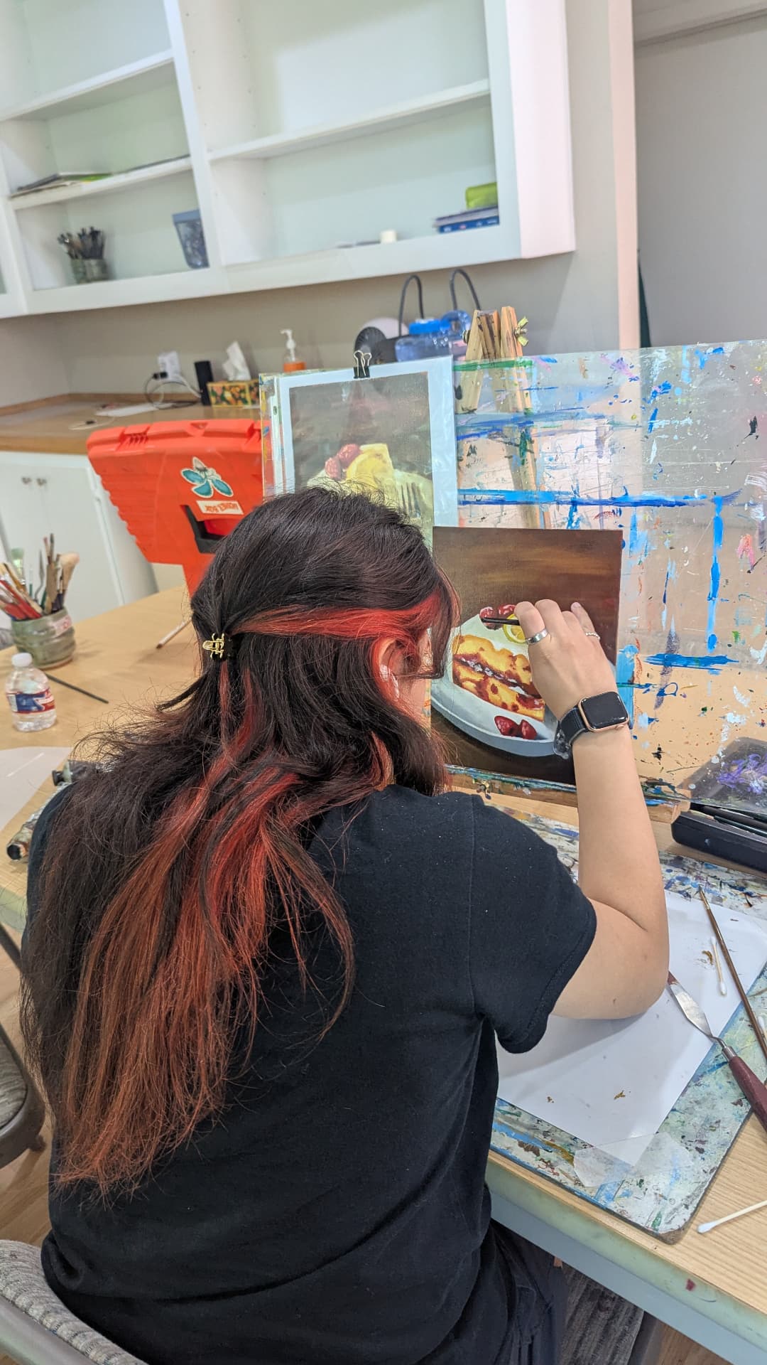 Teen student working on an oil painting of a strawberry dessert